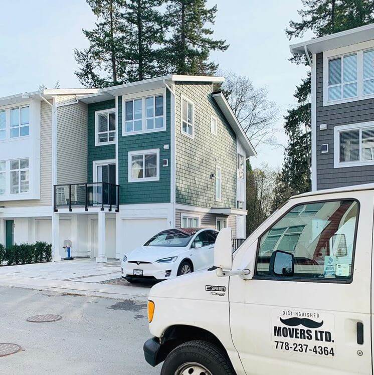 Distinguished Movers truck parked in front of townhouses